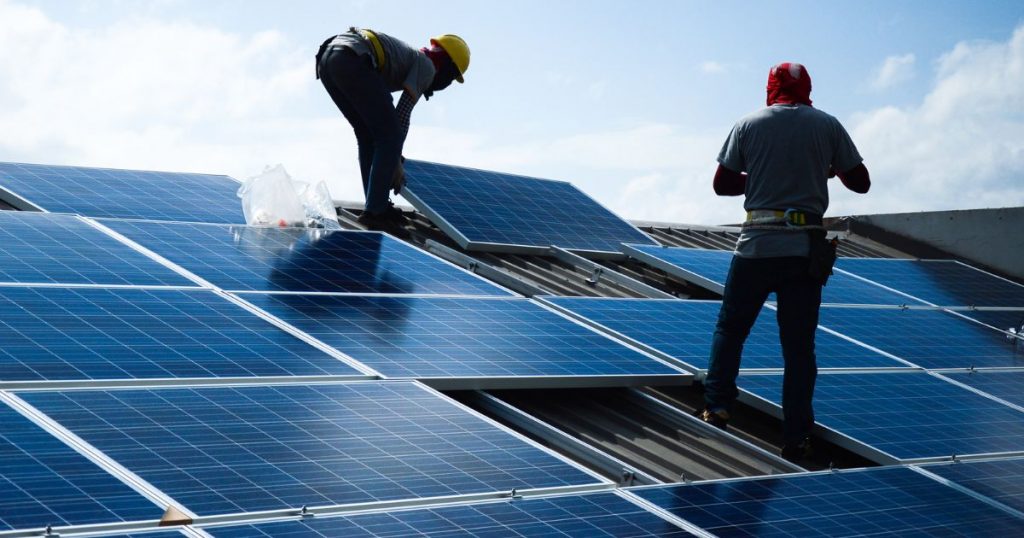 Werkmannen plaatsen zonnepanelen op dak