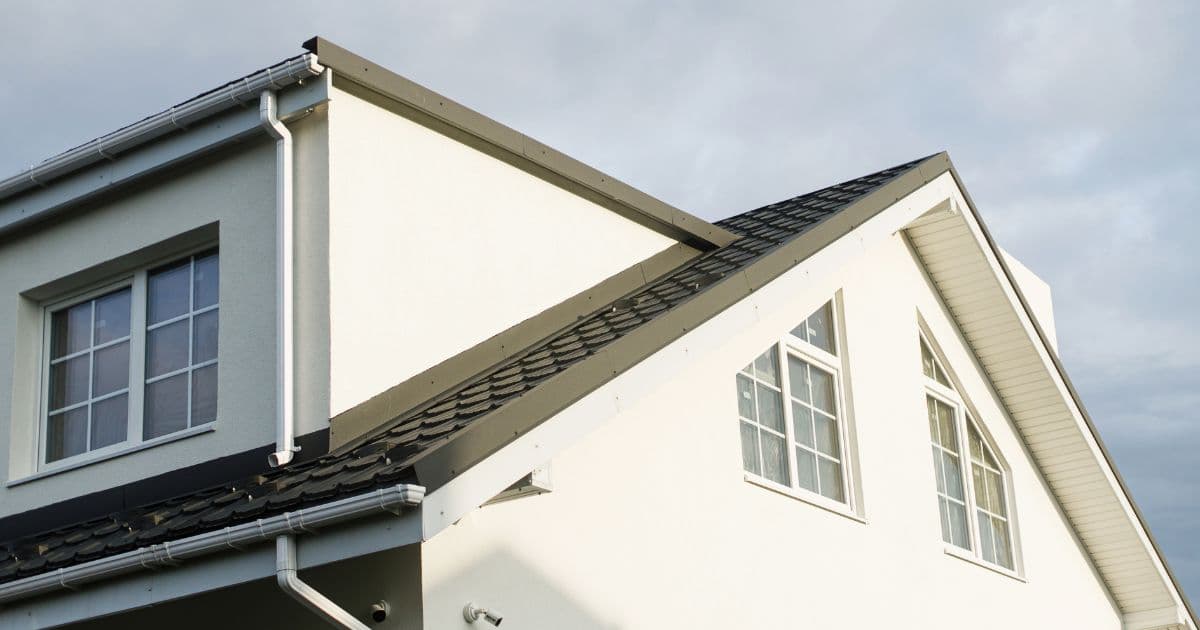 Een volledig afgewerkte dakkapel op een dak met zwarte dakpannen in dezelfde stijl als de rest van de woning.