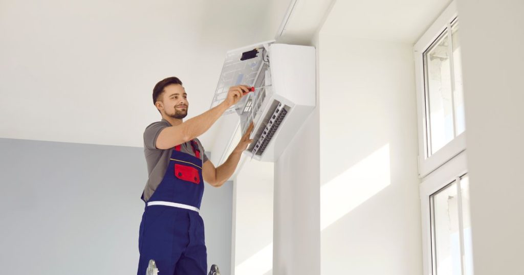 Vloerverwarming of airco? Deze installateur helpt je bij het kiezen van het juiste systeem. Hier installeert hij een airconditioning unit aan de muur.