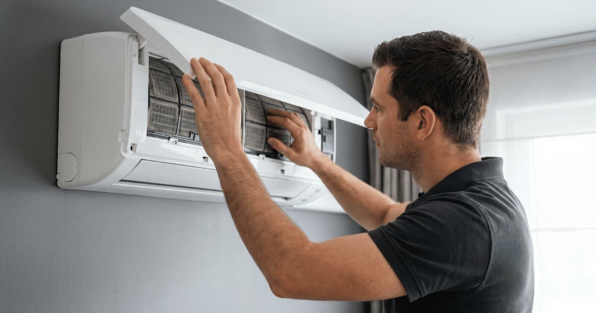Vakman reinigt de binnenunit van een airco in een woning.
