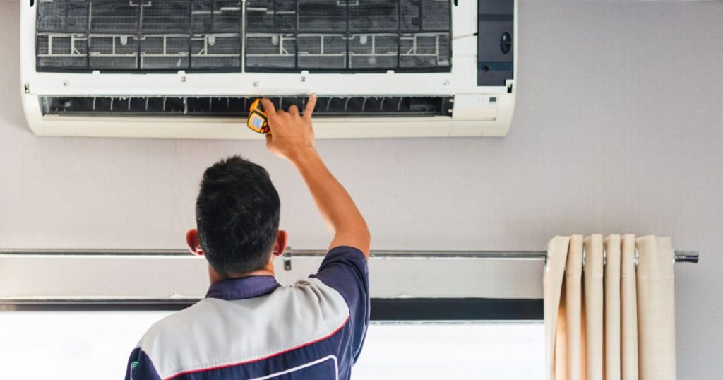 Een erkende aircospecialist installeert een airco in huis boven een raam.