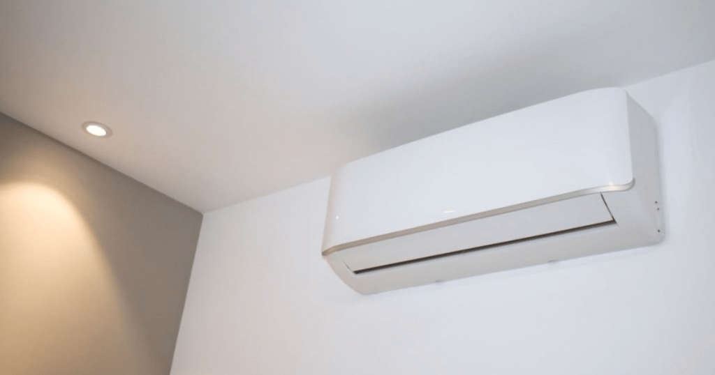 Witte split-unit airco in een woonkamer, tegen een witte binnenmuur. 