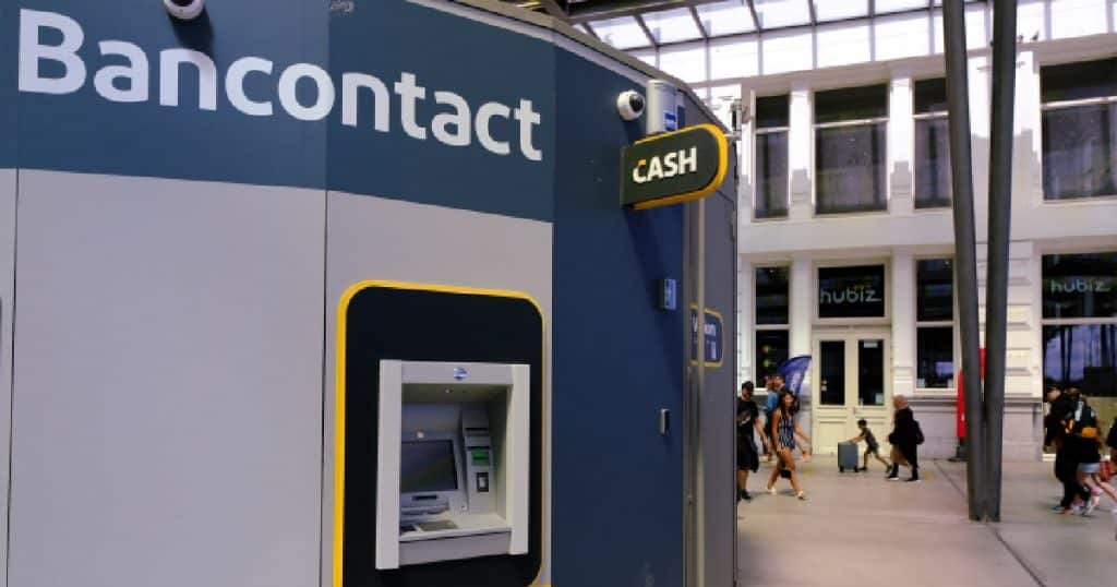 Een grijs met blauwe Bancontact kiosk met geldautomaat in een station.