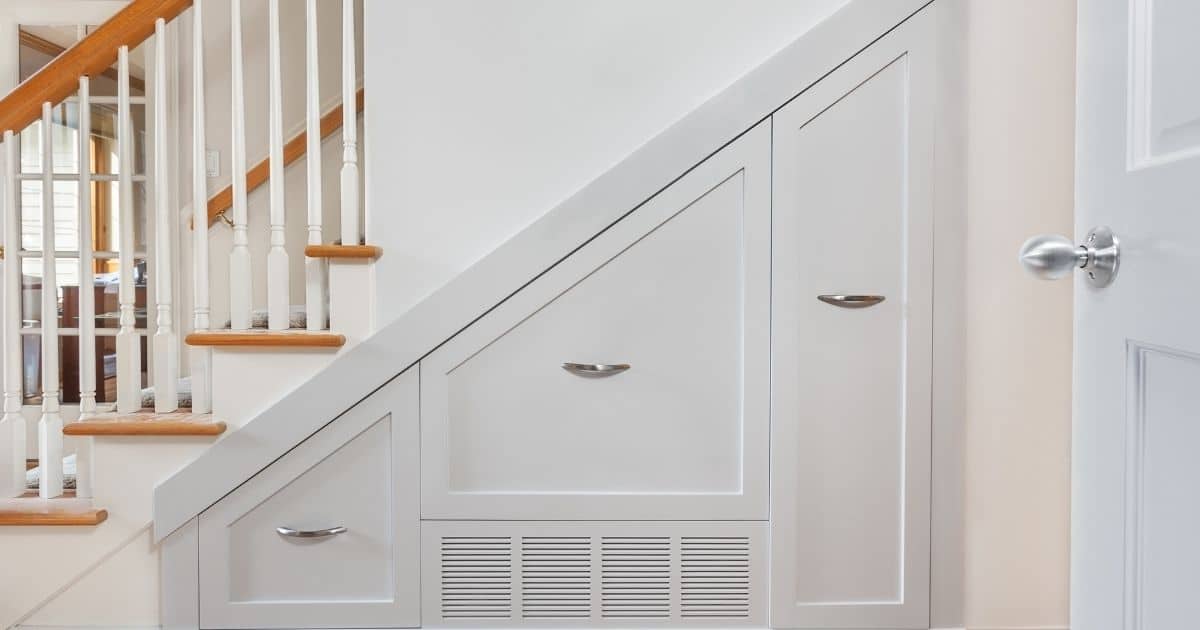 Een witte inbouwkast onder een trap.