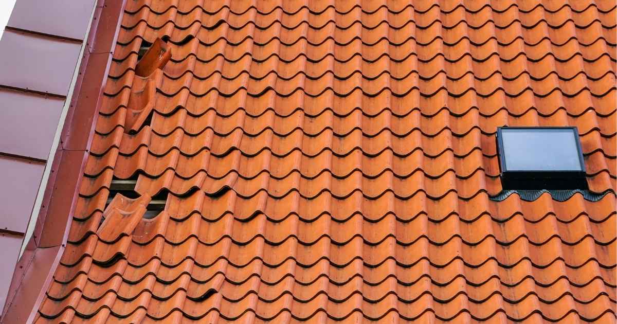 Een beschadigd pannendak met dakraam en loszittende pannen: een mogelijke aanleiding tot schade en lekkages.