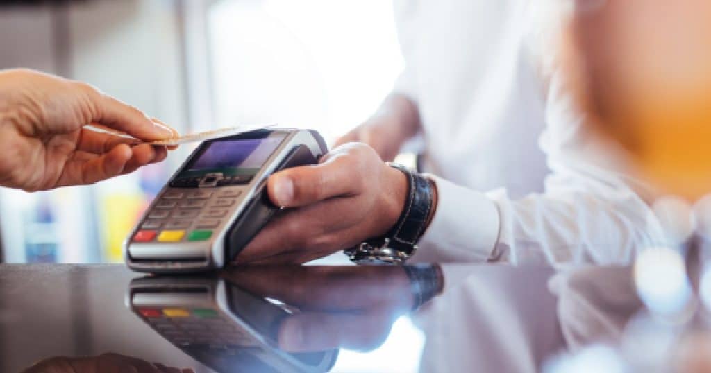 Een man gebruikt zijn debetkaart om af te rekenen via een mobiele betaalterminal.