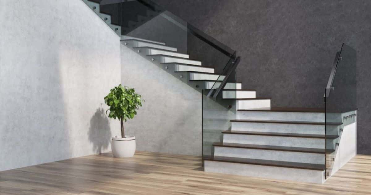 Een trap met een combinatie van beton ciré stootborden en houten traptreden. De trap geeft uit op een houten vloer en is voorzien van een rookglazen trapleuning.