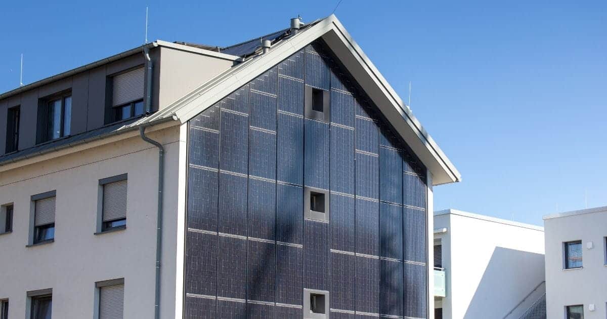 Moderne woning met blauwe geïntegreerde zonnepanelen op de gevel gecombineerd met houten gevelbekleding