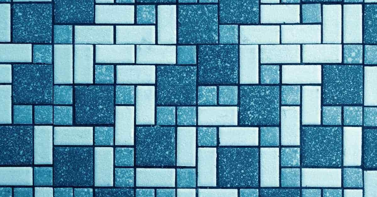 Een muur betegeld met keramische tegeltjes in lichte tot donkere blauwe tinten. De tegels werden in Romaans verband gelegd: een mix van rechthoekige, vierkante en kleine en grote tegels.