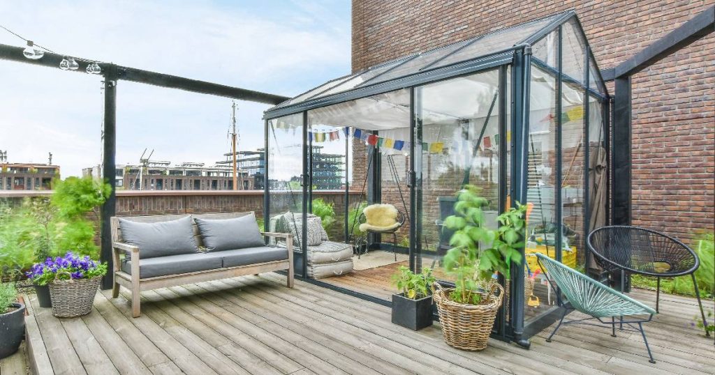Een serre of tuinkamer met zwart aluminium frame en glazen wanden, zoals die van BOzARC. De serre staat op een houten balkon.