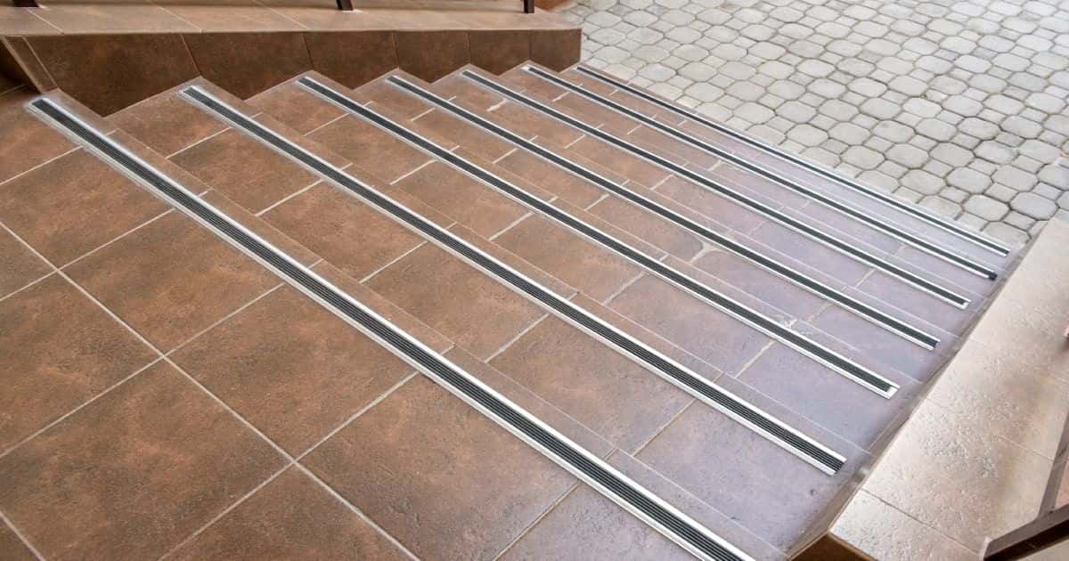 Een bruine buitentrap is voorzien van een antislipstrip op elke trede. Op die manier wordt verhinderd dat gebruikers van de trap bij vochtig of vriesweer kunnen uitglijden op de trap.