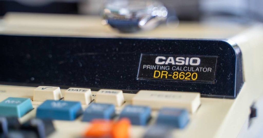 Een beige CASIO printing calculator met kleurrijke toetsen.