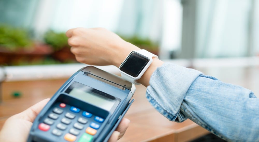 Een jonge vrouw betaalt met haar smartwatch via een betaalterminal met NFC-functie.