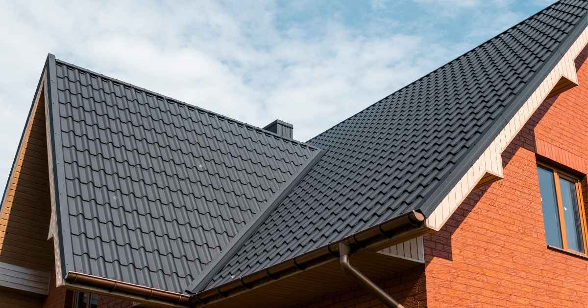 Een woning in oranje baksteen, voorzien van een dak met zinken dakpannen.