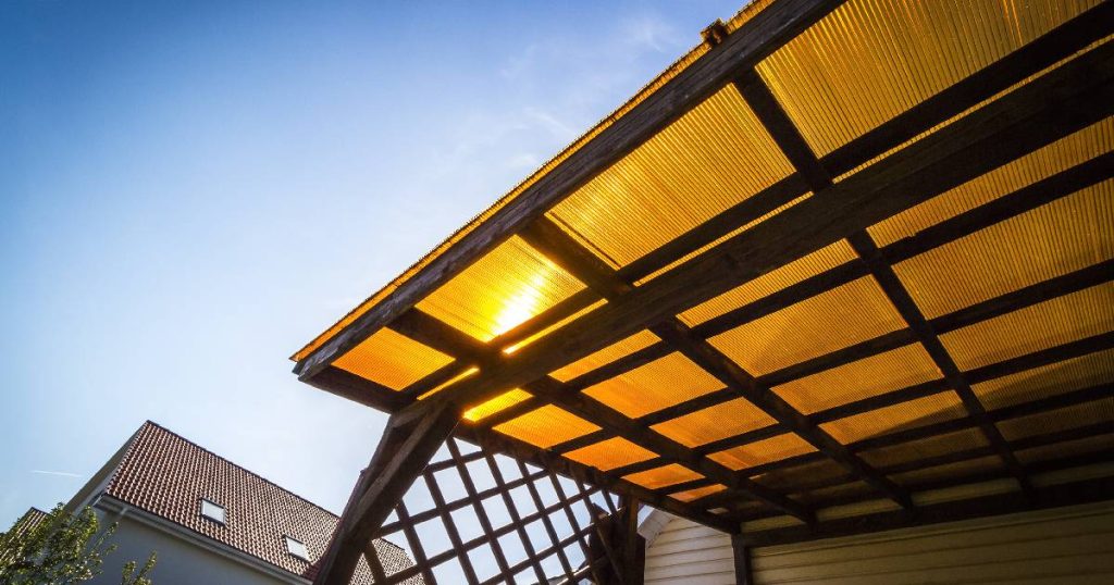 Een open veranda met dakbedekking uit donkergeel polycarbonaat. 