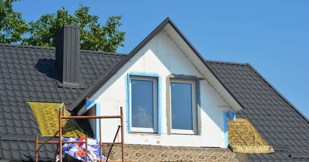 Een dakkapel in volle opbouw: tapijten liggen op het dak zodat de dakwerker comfortabel en veilig kan werken. Ook staat er een steiger, zodat de vakman makkelijk aan de dakkapel geraakt.