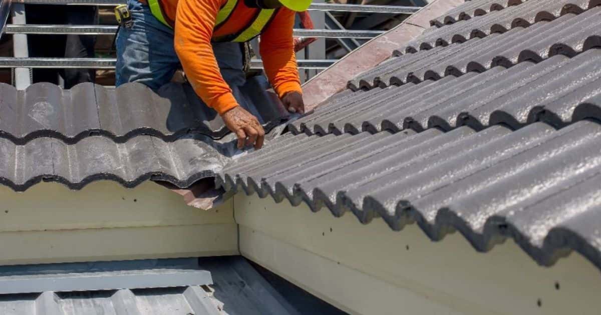 Een dakwerker bekleedt een dak met betonnen dakpannen met coating: pannen met een prijs van 50 à 60 euro per vierkante meter.