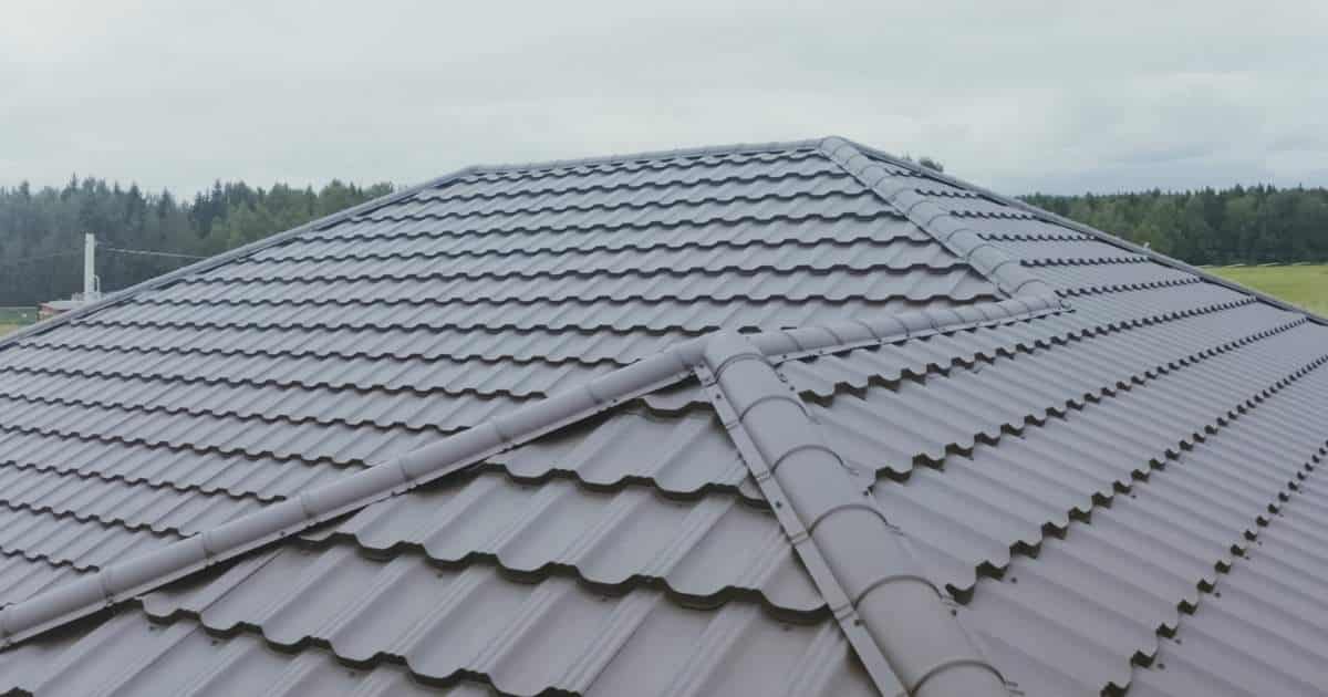 Detail van een donkergrijs dak met sandwichpanelen met dakpanprofiel. De nok is netjes afgewerkt met speciale nokprofielen.