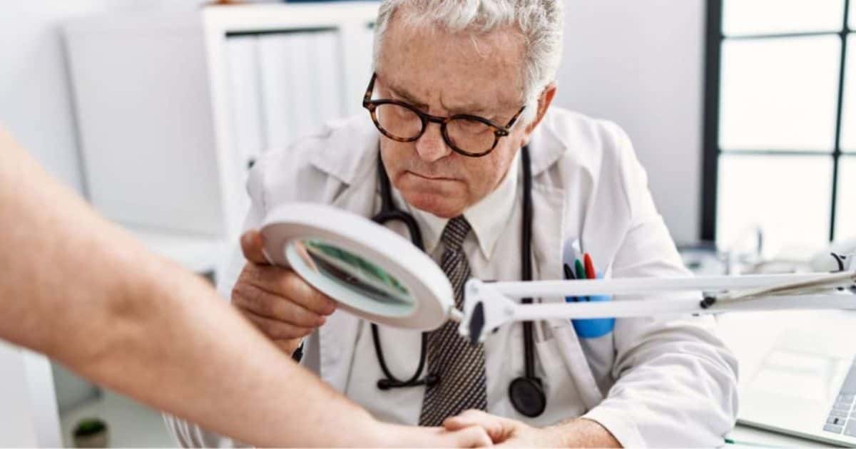 Een dermatoloog aan het werk met een vergrootglas: onderzoek van de huid op arm en/of hand.