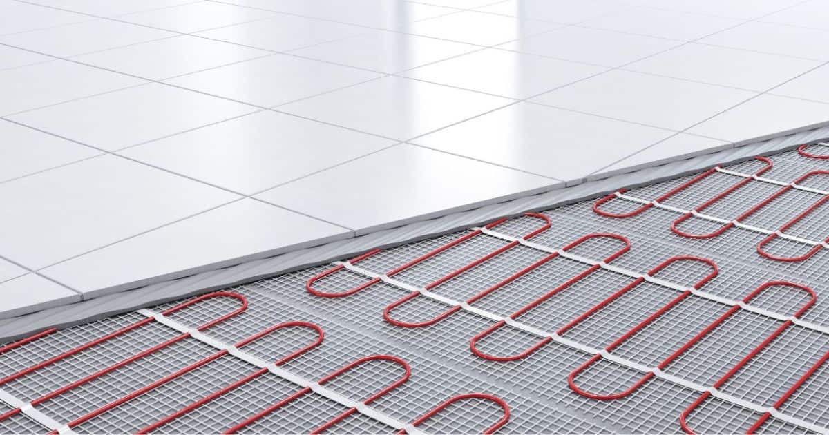 Detailbeeld van een vloer met vloerverwarming: linksboven de witte tegels waaronder de verwarming ligt, rechtsonder de onbedekte vloerverwarming.