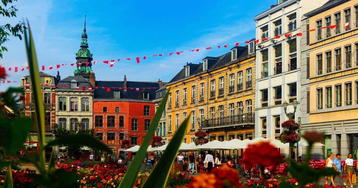 Zicht op de kleurrijke, historische gebouwen in het stadscentrum van Doornik. Er hangen ook rode vlaggetjes boven het plein.