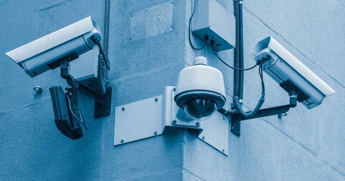 Een dome-camera hangt tussen 2 turret- of bullet-camera's tegen de grijze gevel van een bedrijf.