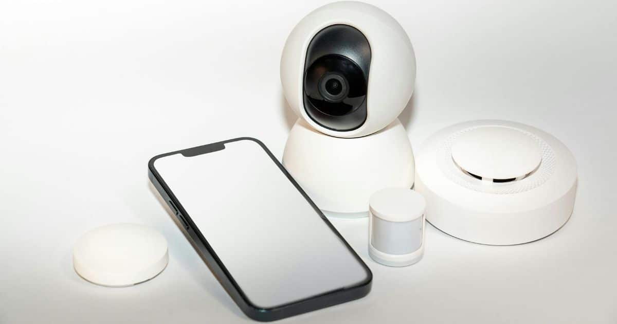 Een draadloze set met bolle bewakingscamera, smartphone en accessoires tegen een witte achtergrond.