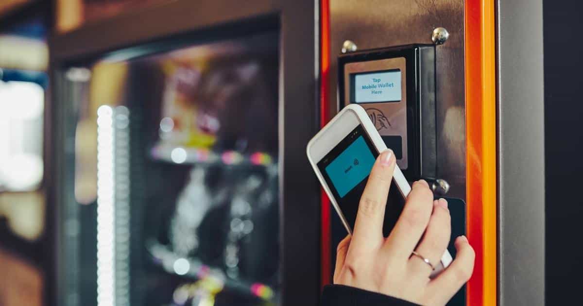 Een dame gebruikt haar smartphone om te betalen bij een drankautomaat.