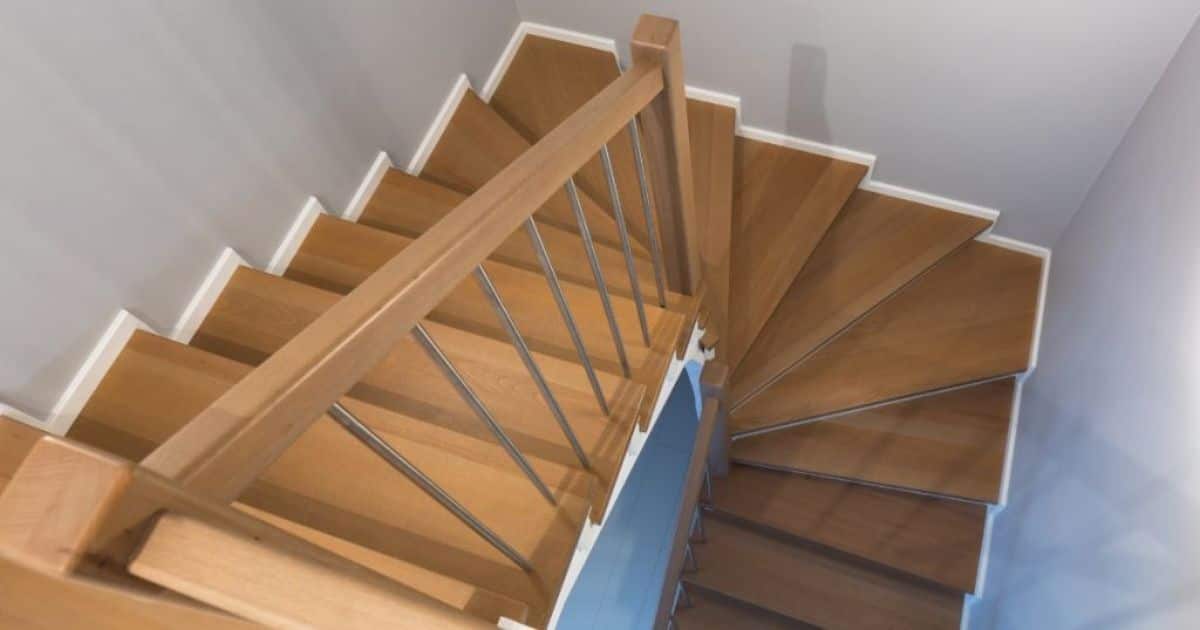 Dubbelkwart trap met houten treden en een houten leuning. De spijlen van de trap zijn van inox of metaal.