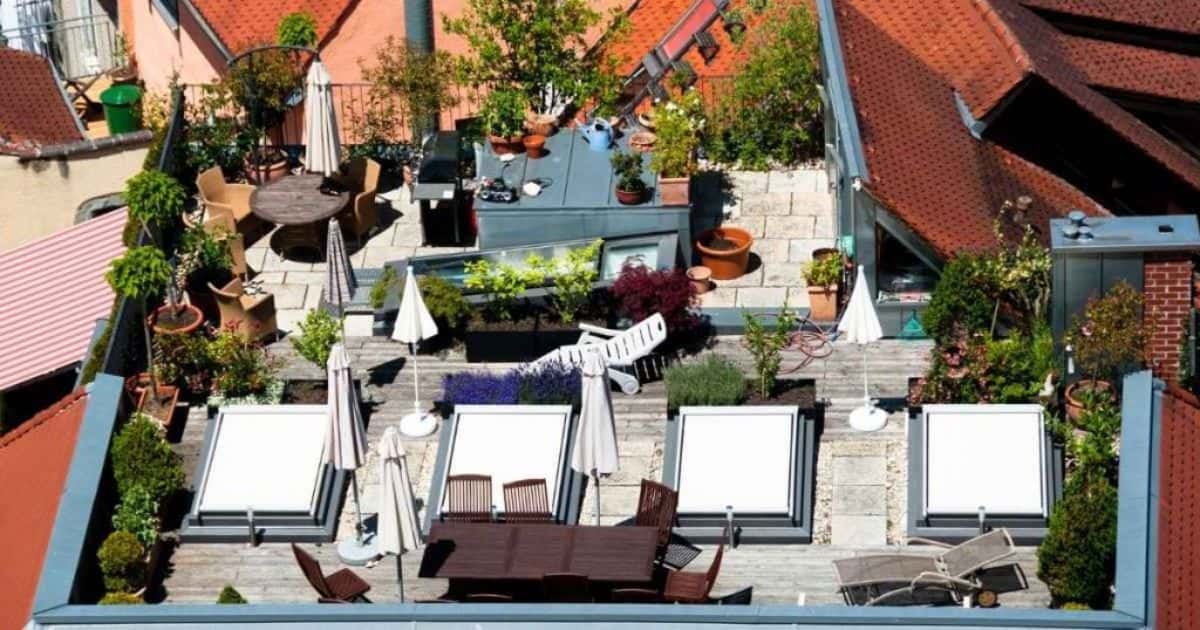 Een gezellig dakterras met houten vloeren, tafels, stoelen en oranje hellende daken