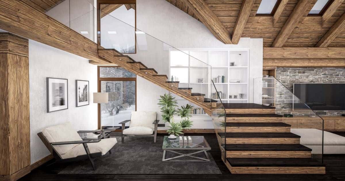 Houten trap met glazen leuning in een woonkamer. De woonkamer heeft overal houten accenten: houten balken  in het plafond. Er staat een groene plant onder de trap. 