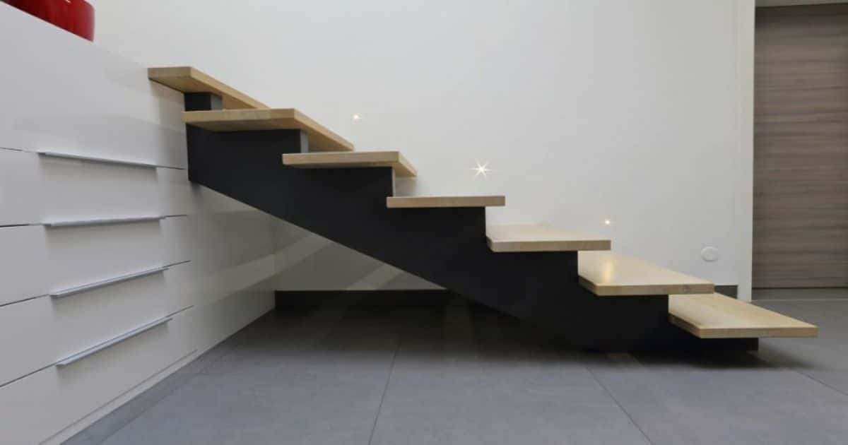 Moderne trapkast. De muren zijn wit, de traptreden zijn beige en de ondersteuning is zwart. De traptreden worden ook verlicht. 