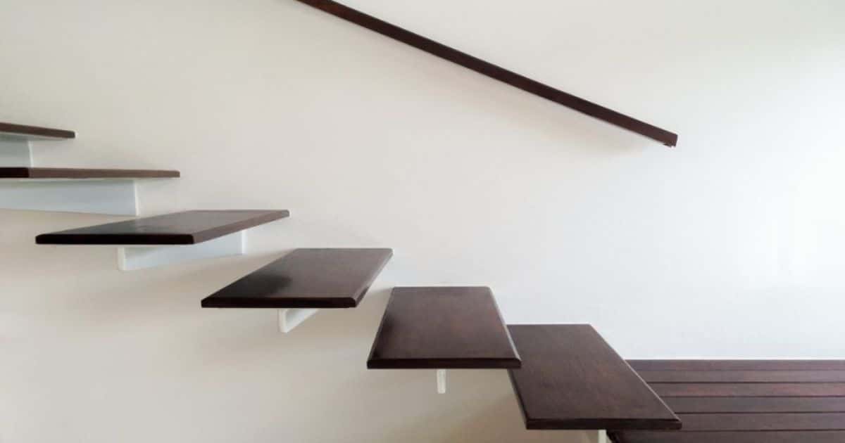 Zwevende eikenhouten trap met open treden en minimalistische design tegen een witte muur.