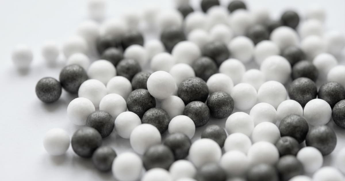 Witte en grijze grafiet EPS-isolatieparels naast elkaar, gebruikt voor spouwmuurisolatie.