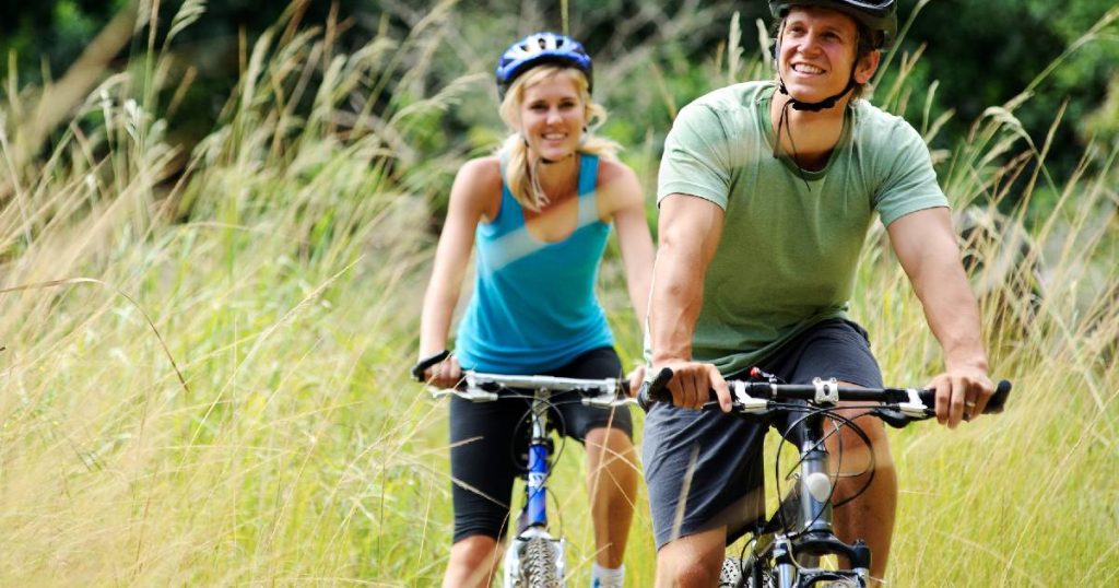 Een koppel fietst door de natuur, ook op vakantie verzekerd met hun omnium fietsverzekering.