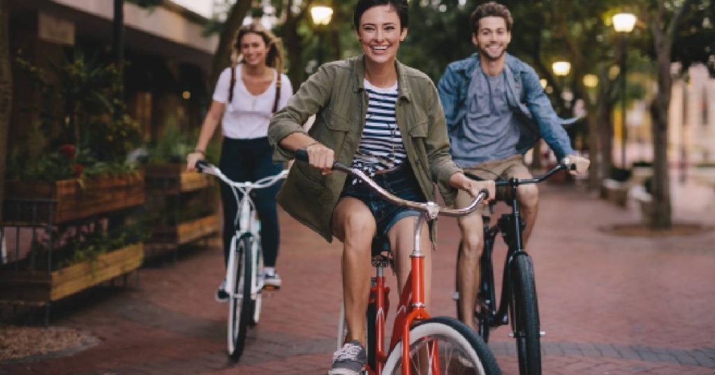Drie jongeren op fietsen in de stad, goed verzekerd dankzij hun fietsverzekering.