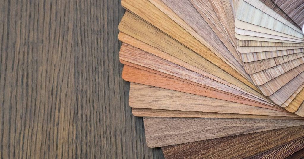 Staaltjes fineerparket in verschillende kleuren en houtsoorten op een donkerbruine houten vloer.