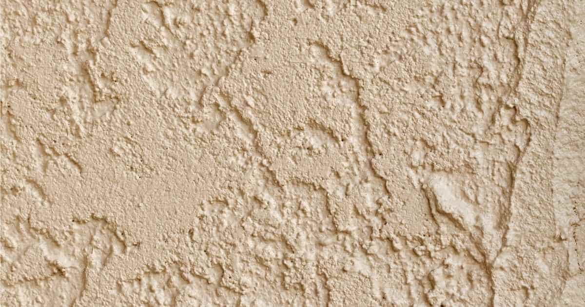 Detailbeeld van een buitengevel afgewerkt met cementpleister dat in de massa werd gekleurd met een gelig pigment.