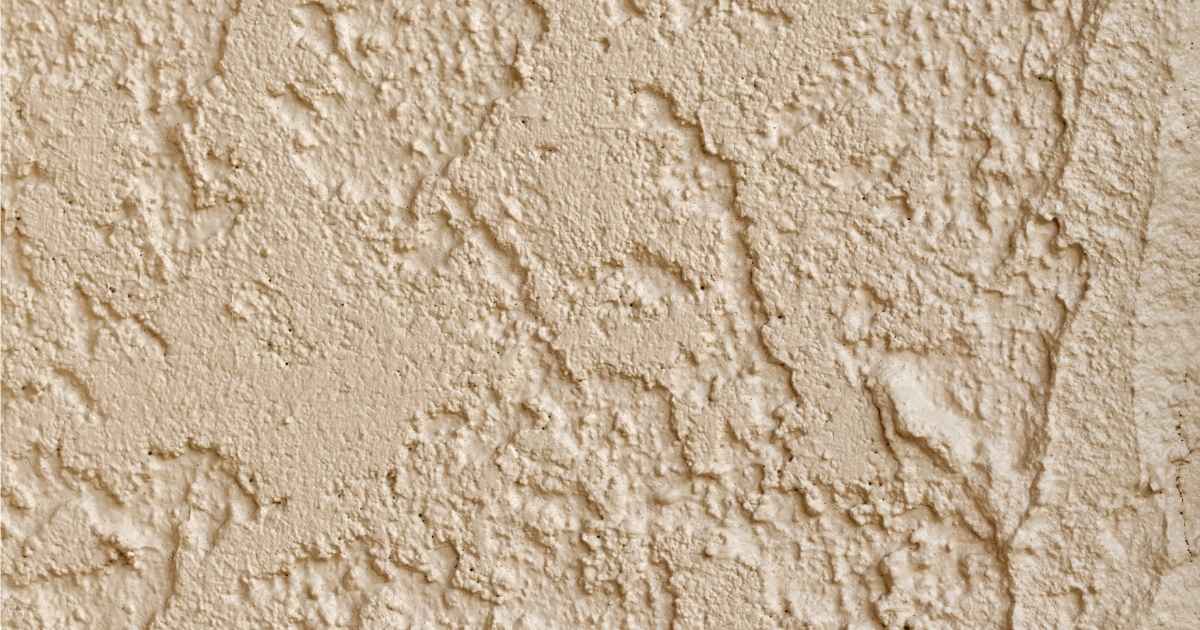 Detailbeeld van een buitengevel afgewerkt met cementpleister dat in de massa werd gekleurd met een gelig pigment.