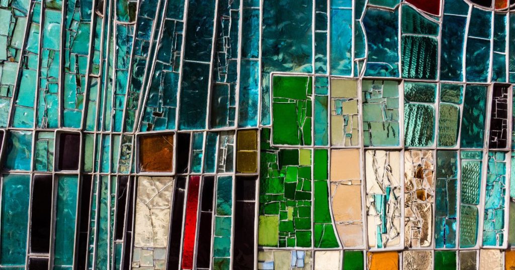 Detailbeeld van gekleurd spiegelglas: de onregelmatige vorm en het gerafelde karakter van het spiegelglas geeft het een geheel kunstzinnig karakter.