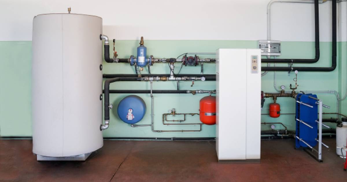 Een geothermische warmtepompinstallatie in een kelder of garage met een donkerrode vloer en wit met mintgroene muren