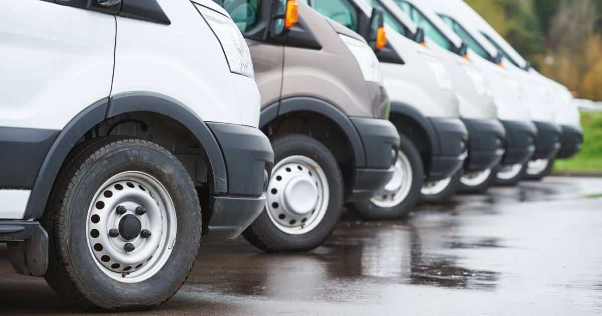 Een rij met witte en grijze geparkeerde bestelwagens of bedrijfsvoertuigen.