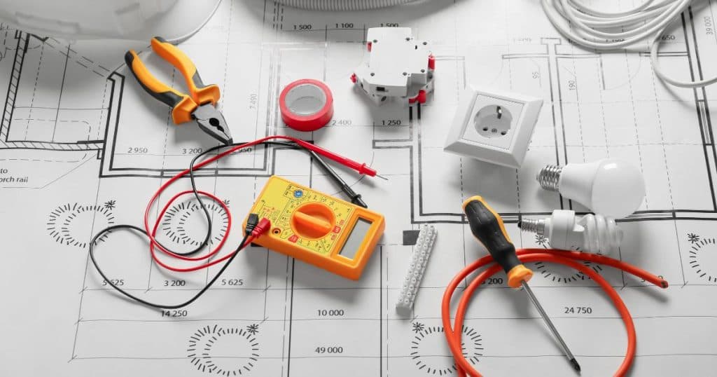 Een eendraadschema van een elektrische installatie met verschillende objecten waaronder een tang, spanningsmeter, spaarlampen en een stopcontact.