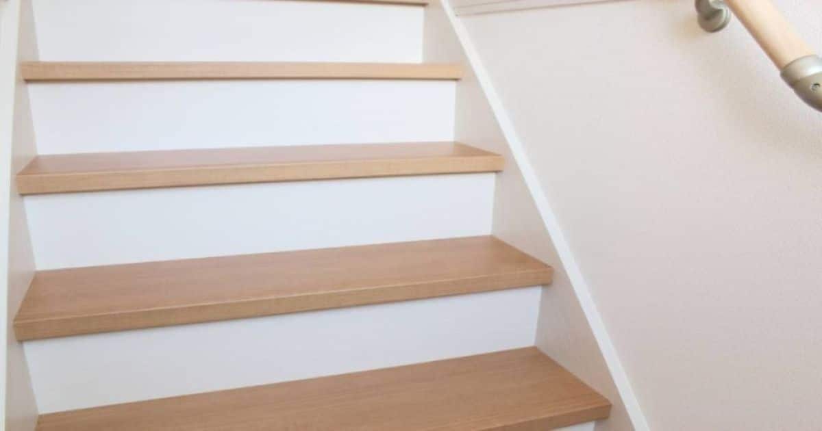 Gesloten witte trap met houten traptreden.