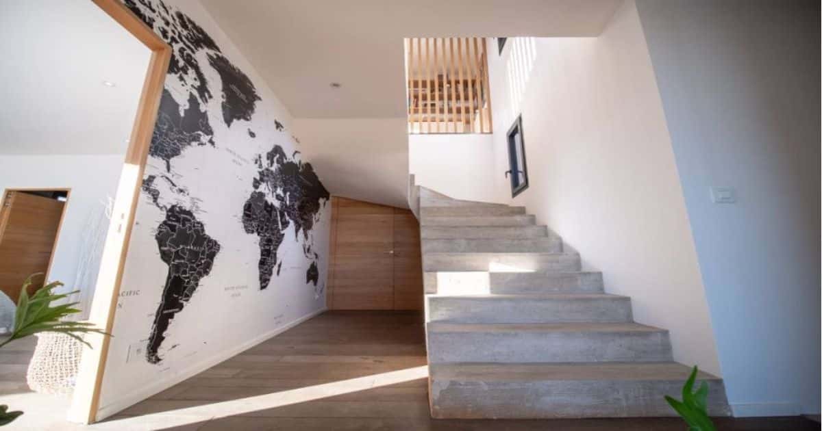 Een nieuwe gesloten trap met betonlook in een bestaande woning. De grijze kleur van de trap vormt een mooi geheel met de witte muren en de houtelementen her en der.