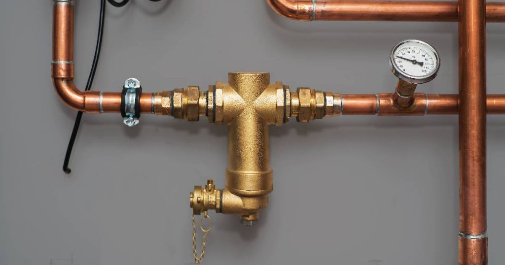 Een magnetische waterontkalker bevestigd op een koperen waterleiding met waterdrukmeter.