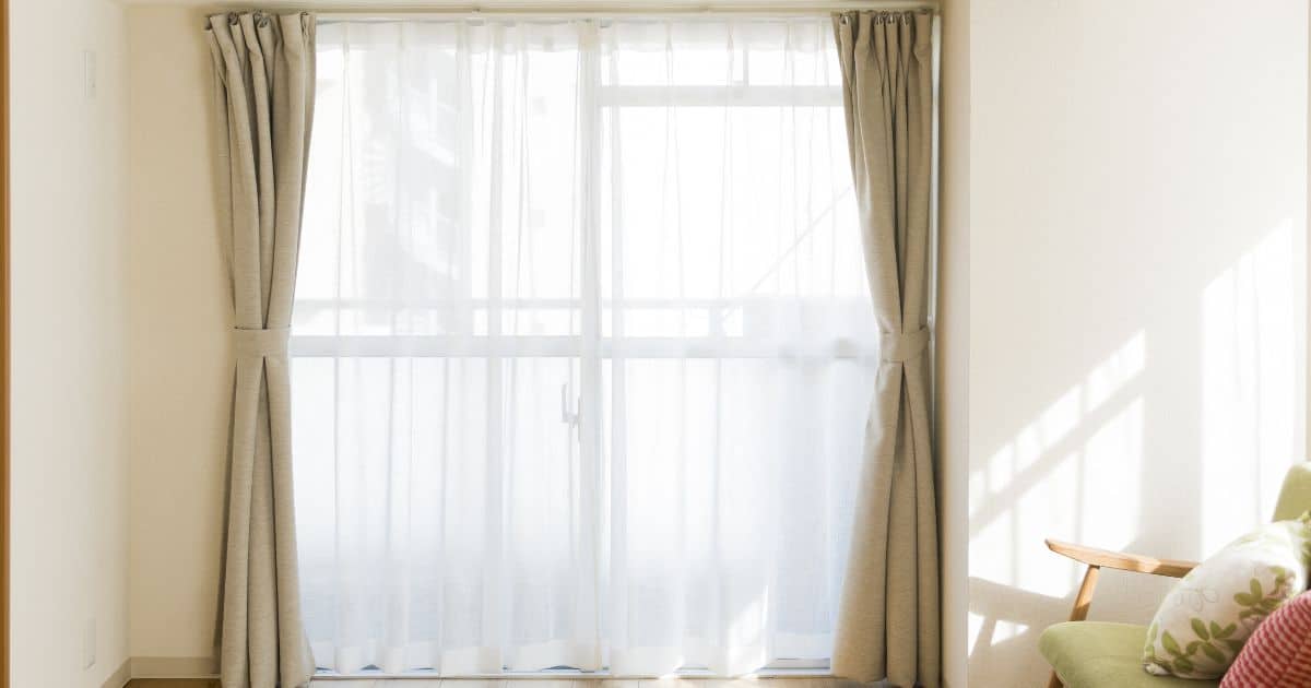 De combinatie van lichtdoorlatende gordijnen en de licht geverfde muren zorgen ervoor dat de kleine kamer fris en groot aanvoelt.