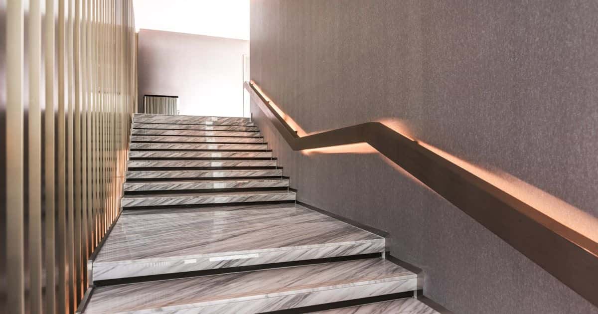 Een trap die men heeft laten bekleden met natuurstenen tegels en heeft voorzien van een trapleuning met ledverlichting.