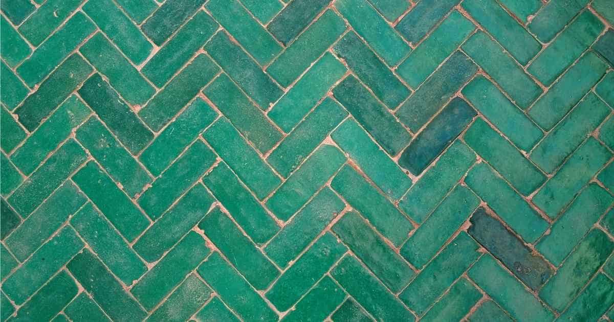 Een vloer met lange tegels in groene tinten, gelegd in visgraatpatroon.