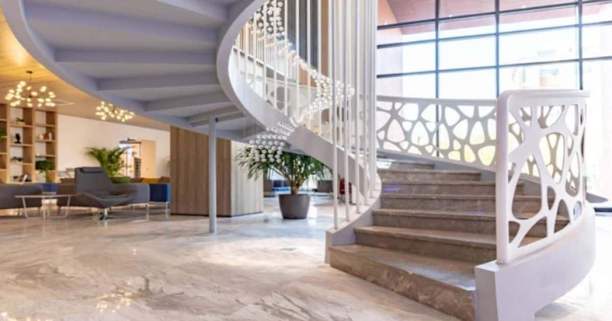 Grote witte wenteltrap met decoratieve balustrade en houten treden  in een modern interieur.